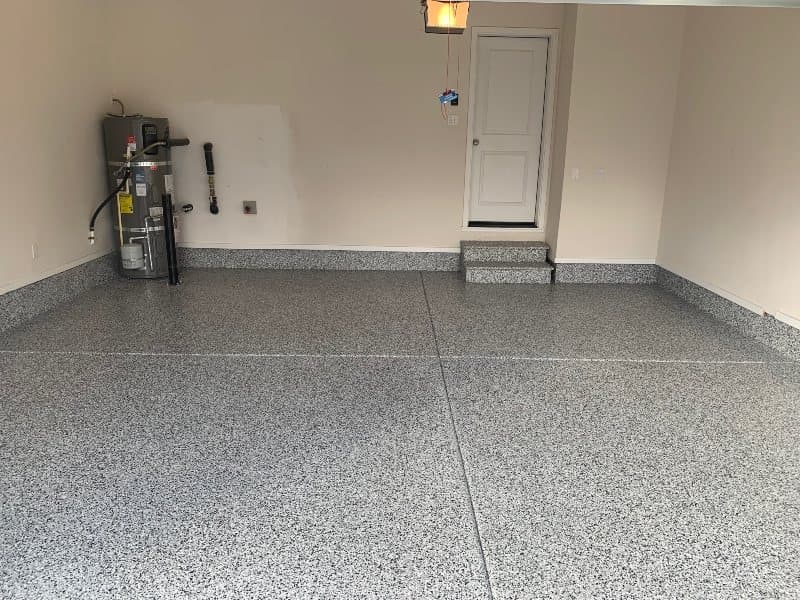 Black, white and grey flake garage floor with matching coated steps leading to a white door.