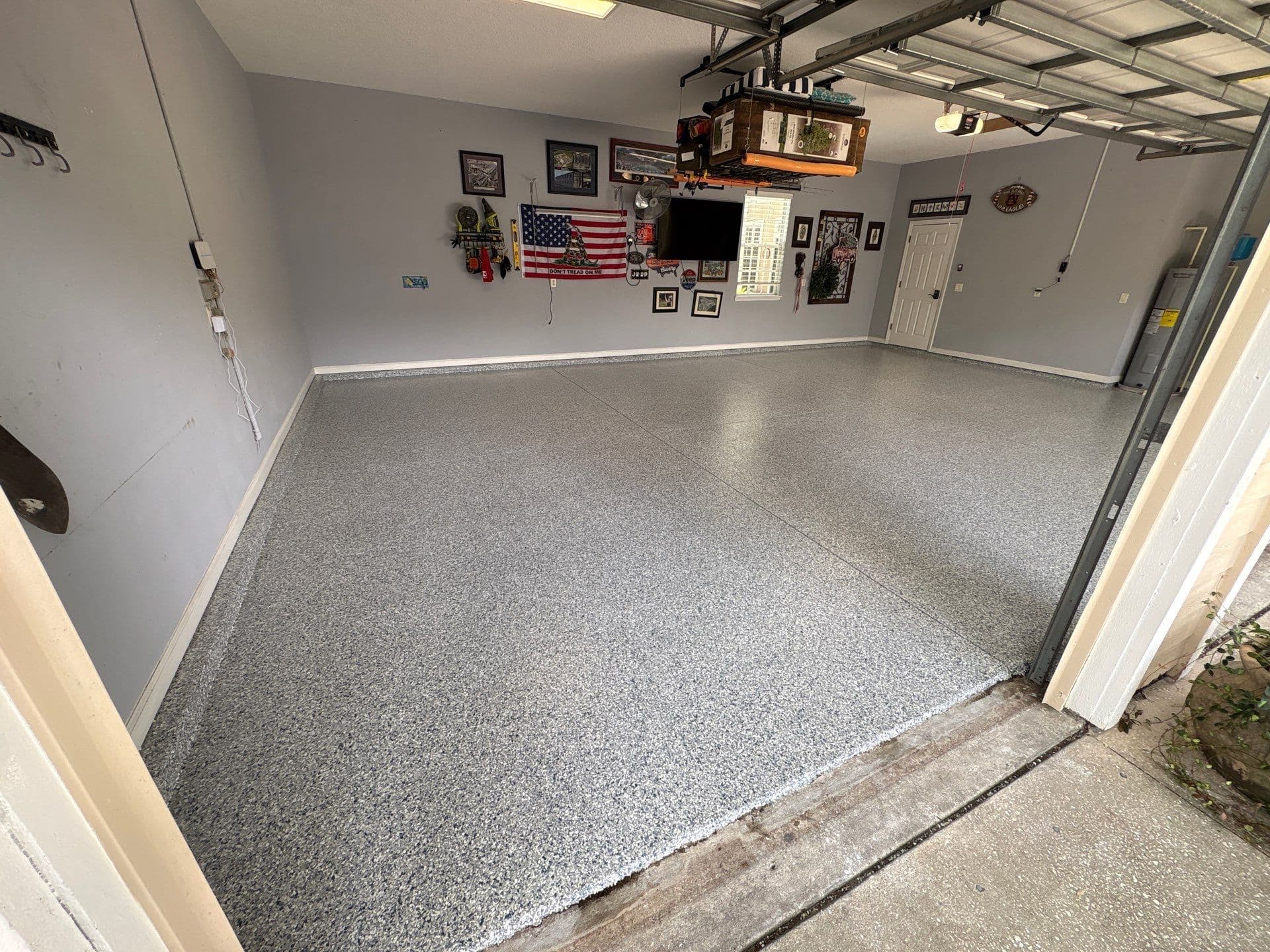 Light grey flake floor in an open garage with wall decorations and overhead storage.